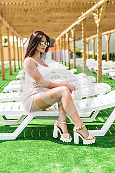 Pretty brunette woman relaxing on a lounger outdoors near pool