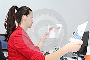 Pretty Business woman analyzing investment charts with calculator and laptop