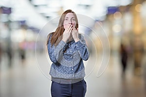 Pretty business woman covering her mouth over blur background.