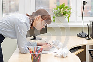 Pretty business woman in glasses in the office at the work table signs documents