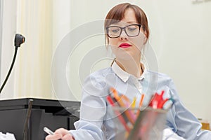 pretty business woman in glasses in the office at the work table signs documents
