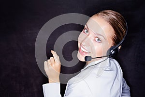 Pretty business woman with a headset on black , copyspace. Happy young business executive with a headset isolated