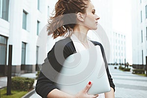Pretty business woman hold modern laptop and stand among urban space