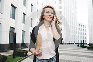 Pretty business woman hold paper documents and discuss financial news on smartphone stand among urban space