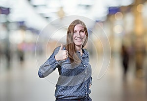 Pretty business woman making ok gesture over blur background