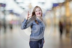 Pretty business woman making ok gesture over blur background
