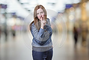 Pretty business woman making silence gesture over blur background