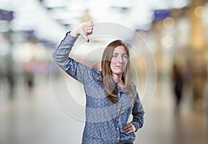 Pretty business woman making thumb down gesture over blur background