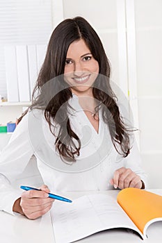 Pretty business woman smiling at desk in her office