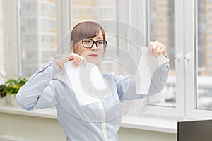 pretty business woman in strict stylish clothes and glasses in the office near the desktop tearing documents