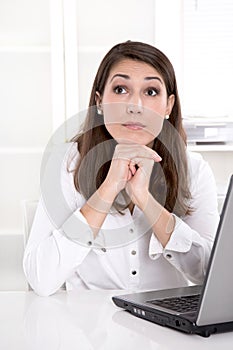 Pretty businesswoman dreaming in front of laptop