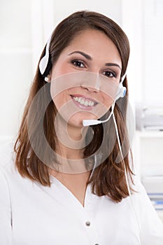 Pretty businesswoman in white sitting at helpdesk and laptop wit