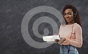 Pretty call center worker with headphones on grey background