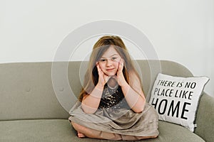 A pretty caucasian girl wearing gray dress and sitting on the gray sofa