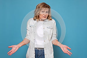 Pretty caucasian mature woman looking confused shrugging shoulders.