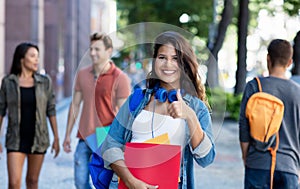 Pretty caucasian young adult woman walking in city with group of students