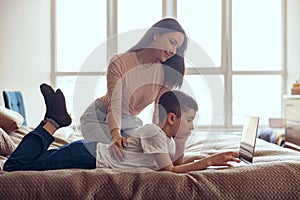 Pretty Caucasian young woman with little cute little son using laptop for searching info.