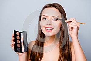 Pretty charming beautiful cute smiling cheerful happy joyful woman is doing make up and applying eyeshadows, she is going on a da