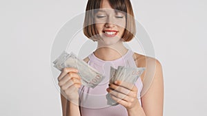 Pretty cheerful girl with bob hair look happy counting money on camera isolated on white background