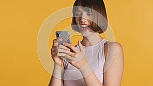 Pretty cheerful girl enjoy online chatting with friends in social network isolated on yellow background. Happy