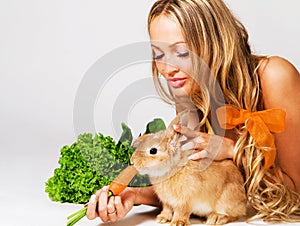Pretty cheerful girl feeding a rabbit