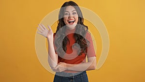 Pretty cheerful girl happily waving hello on camera over colorful background. Greeting expression