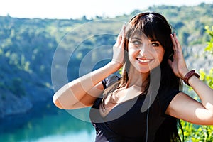Pretty cheerful young woman listening to music in headphones outd
