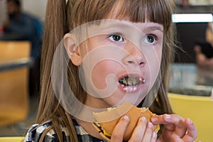 Pretty child girl eating fast food in a restaurant