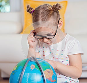 Pretty child girl at home dreaming of travel and tourism, exploring the world and globe