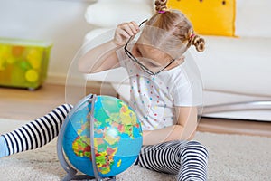 Pretty child girl at home dreaming of travel and tourism, exploring the world and globe