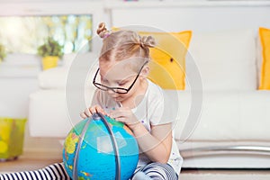 Pretty child girl at home dreaming of travel and tourism, exploring the world and globe
