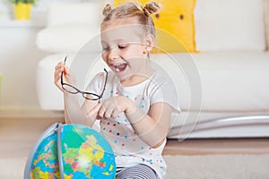 Pretty child girl at home dreaming of travel and tourism, exploring the world and globe