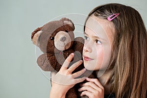 Pretty child girl playing with her teddy bear toy