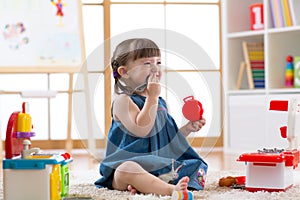 Pretty child girl playing with a toy kitchen in children room
