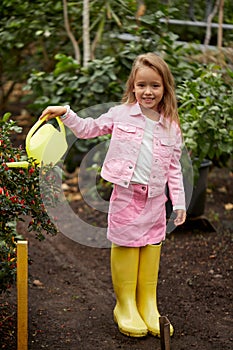 Pretty child girl watering the beds with berries