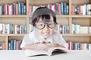 Pretty child with glasses and book in the library