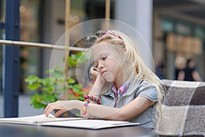 Pretty child reading menu in the cafe