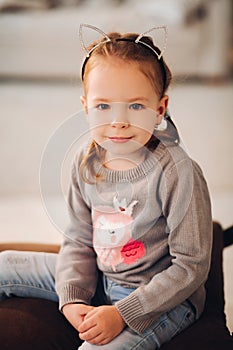 Pretty child sitting on Christmas swing. Christmas tree.