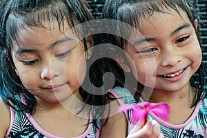 Pretty child twins holding a pink flower. Pretty asian twins portrait with flower and smiling