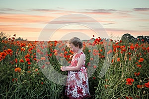 Pretty child young cute girl red dress stood peaceful tranquil poppy flower field landscape view poppies dusk sunset golden hour