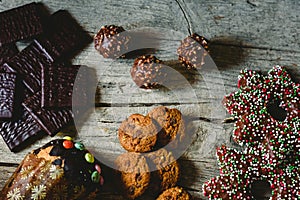 Pretty composition with warm light of Christmas sweets and chocolate cookies, festive background arranged on a rustic wooden table