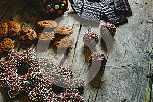 Pretty composition with warm light of Christmas sweets and chocolate cookies, festive background arranged on a rustic wooden table