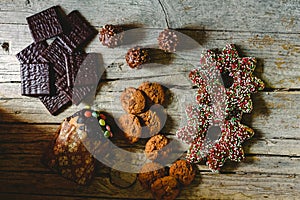 Pretty composition with warm light of Christmas sweets and chocolate cookies, festive background arranged on a rustic wooden table