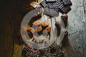 Pretty composition with warm light of Christmas sweets and chocolate cookies, festive background arranged on a rustic wooden table