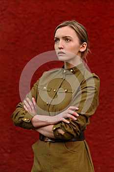 Pretty concentrated girl in Soviet World war II uniform at red w