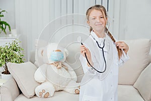 Pretty confident little girl wearing doctor coat, holding stethoscope, pulling her beautiful plait, standing, posing.