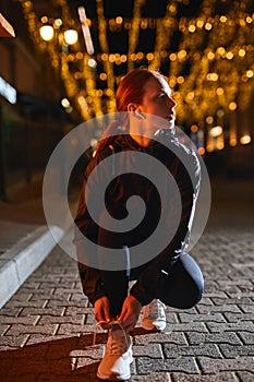 Pretty confident runner woman in sportive wear is preparing for jogging, tie shoelaces