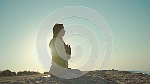 pretty confident woman doing yoga and meditation practicing at sunrise on beach