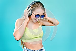 Pretty cool girl having fun and listens to music in the headphones on smartphone over colorful background.