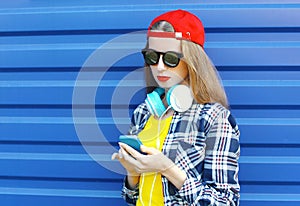 Pretty cool girl listens to music in headphones and using smartphone